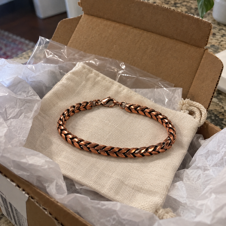 Braided copper chain bracelet resting on a linen gift pouch in its shipping box